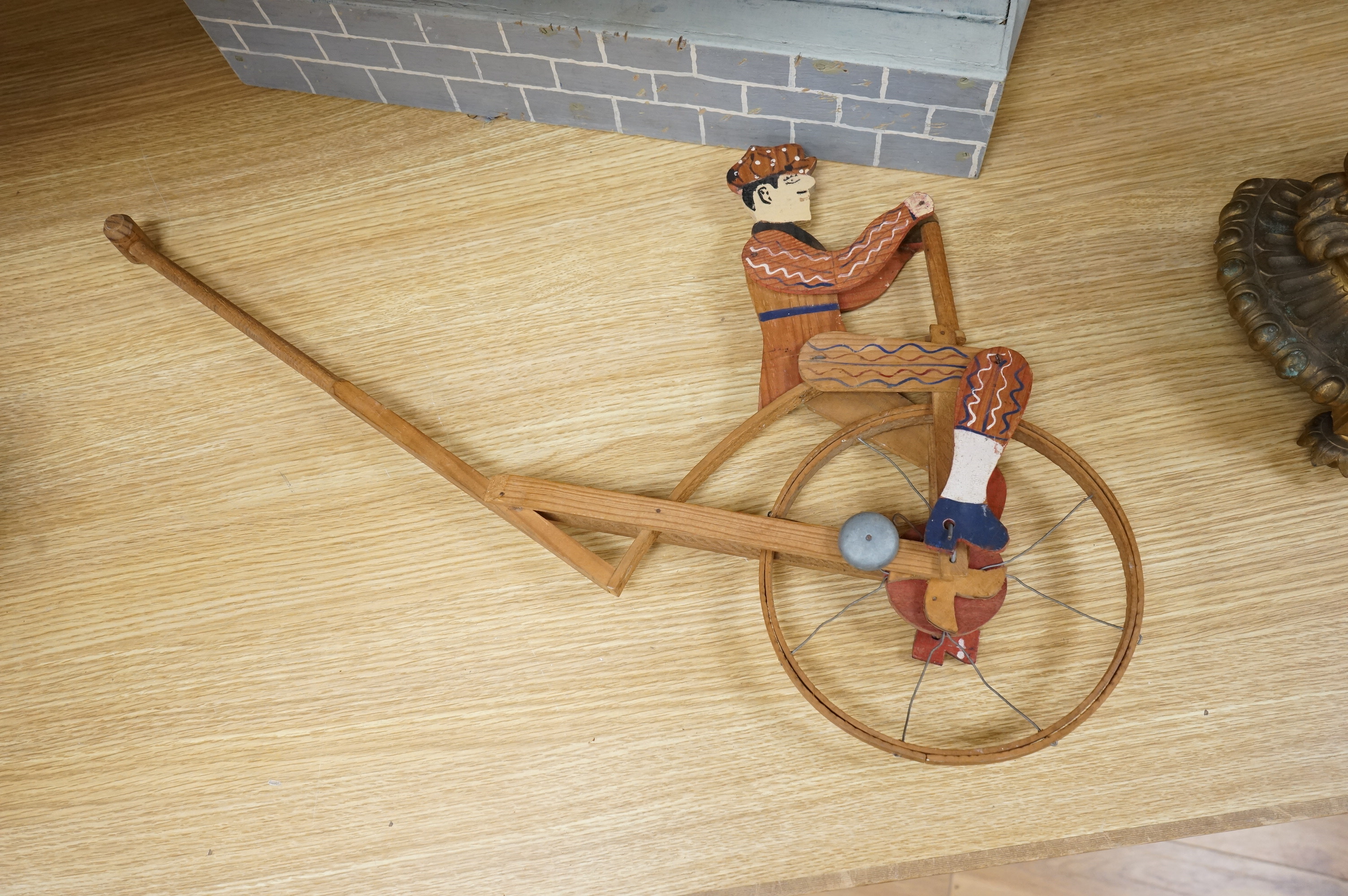 A decorative painted wood articulated ‘soldiers’ toy and another penny farthing toy